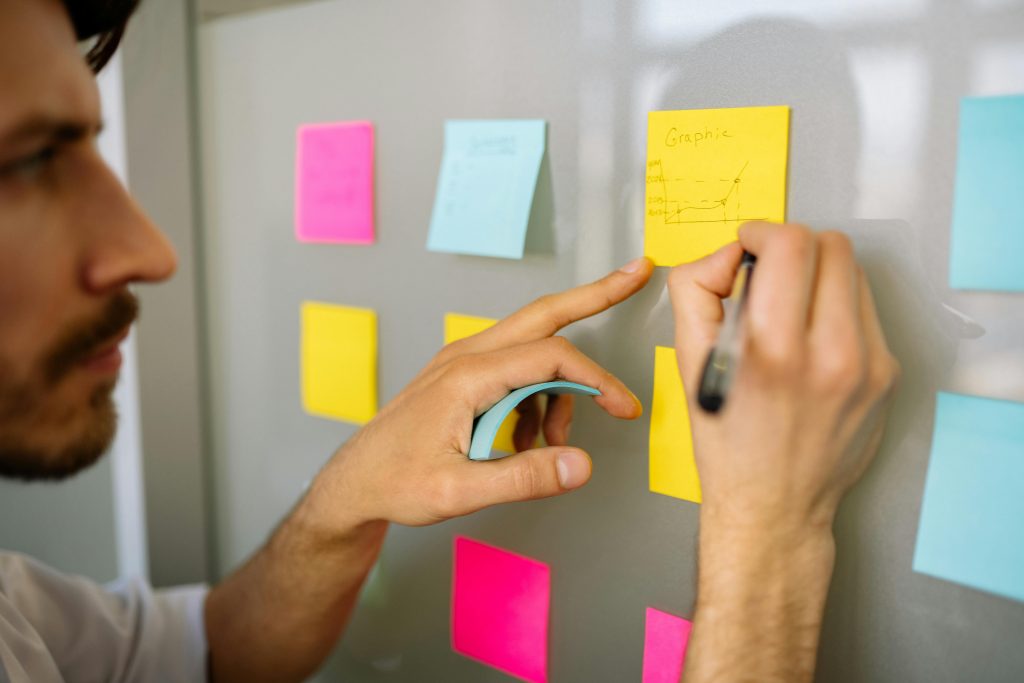 pexels-photo-7793696-7793696 Focused businessman writing ideas on sticky notes for planning and organization.